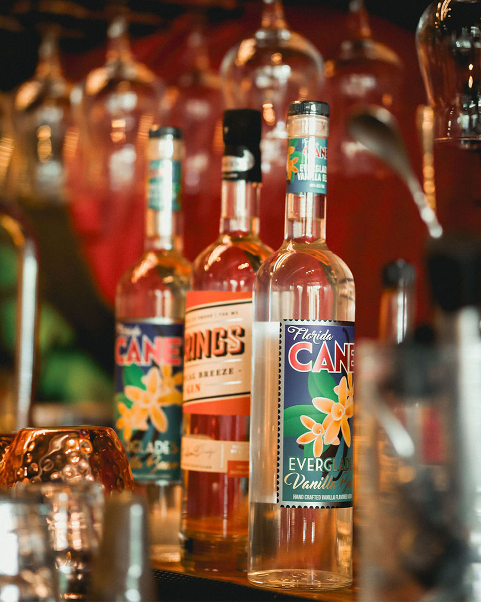3 Rum cocktail mix bottles lined up next to each other on a bar top.